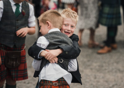 Two paige boys in kilts hugging after a wedding