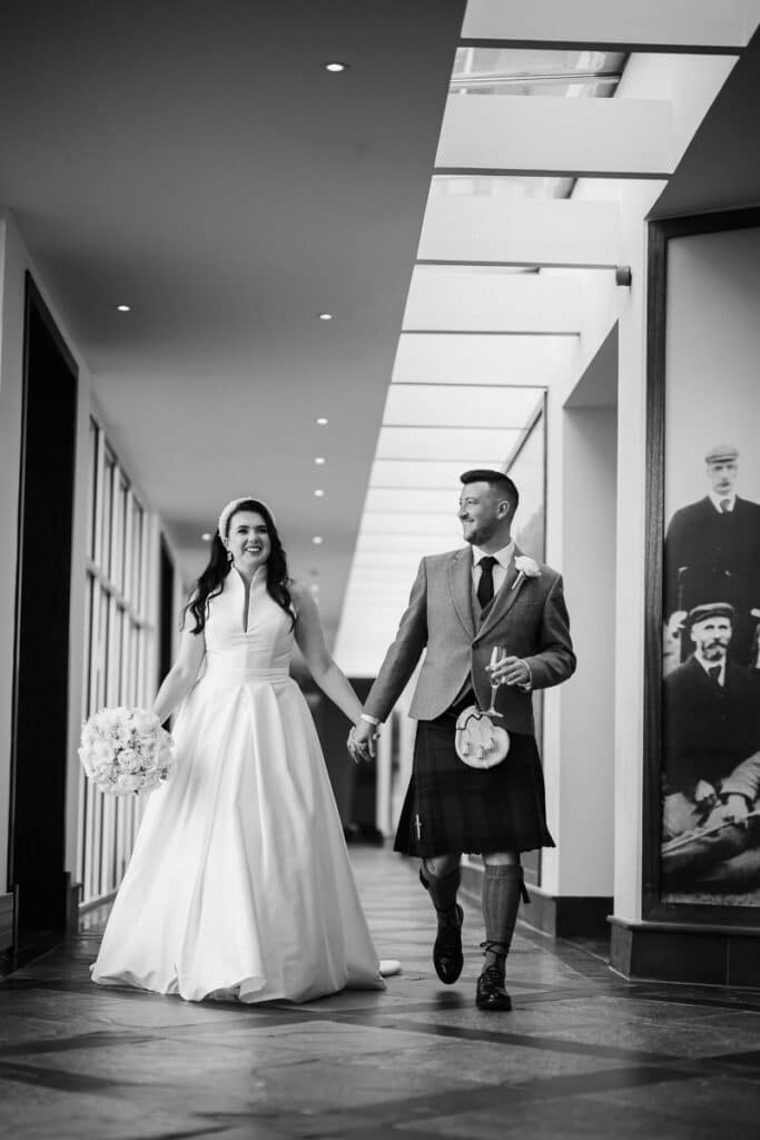 Bride and groom walk together down a corridor of the Old Course Hotel