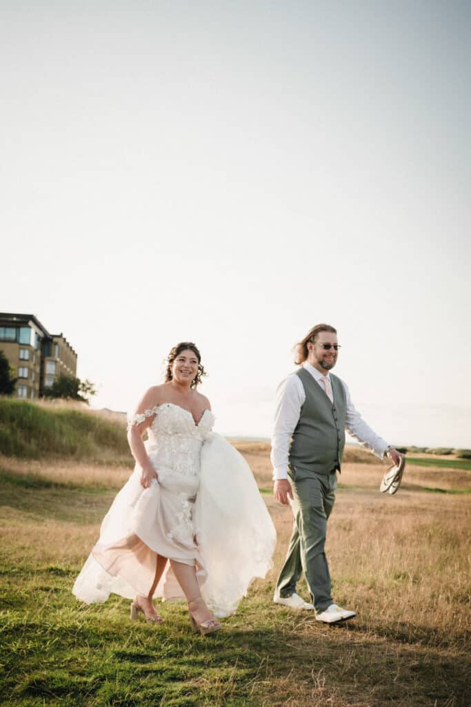 Bride and groom walk together during the day outside the Old Course Hotel in St Andrews