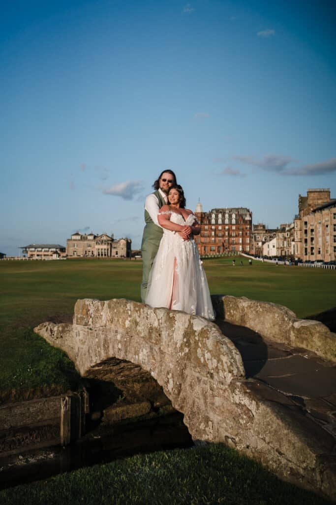 Bride and Groom stand on the Swilcan Bridge during their wedding at the Old Course Hotel