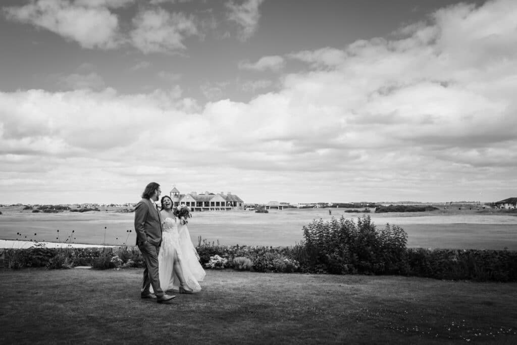 Black and white image of bride and groom walking through the grounds of the Old Course Hotel