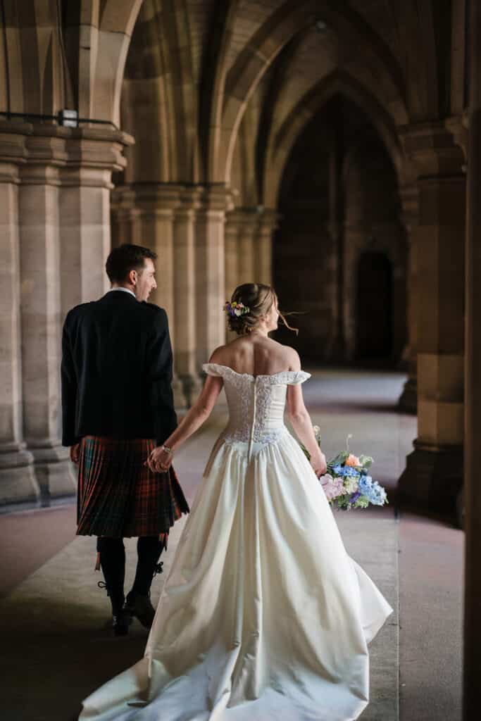 Bride and Groom walk through the cloisters of Glasgow University