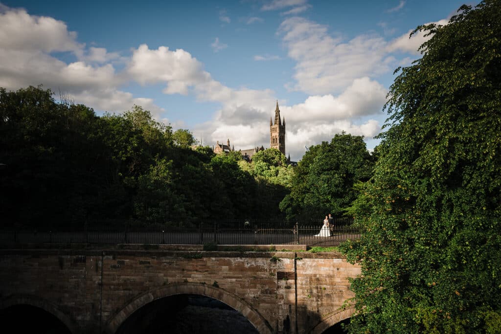 Bride and groom small in the frame with Glasgow university behind them