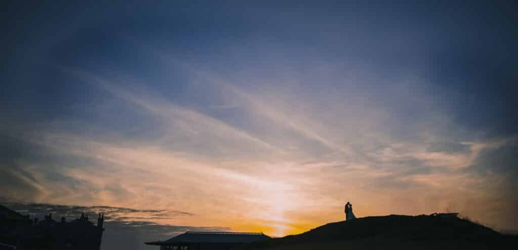 Overlooking the Old Course, a bride and groom are silhouetted by the setting sun