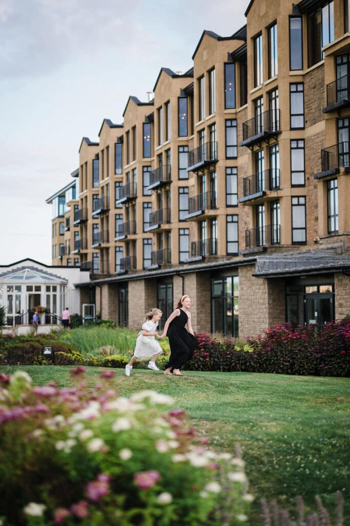 2 young flower girls run through the grounds of Old Course Hotel