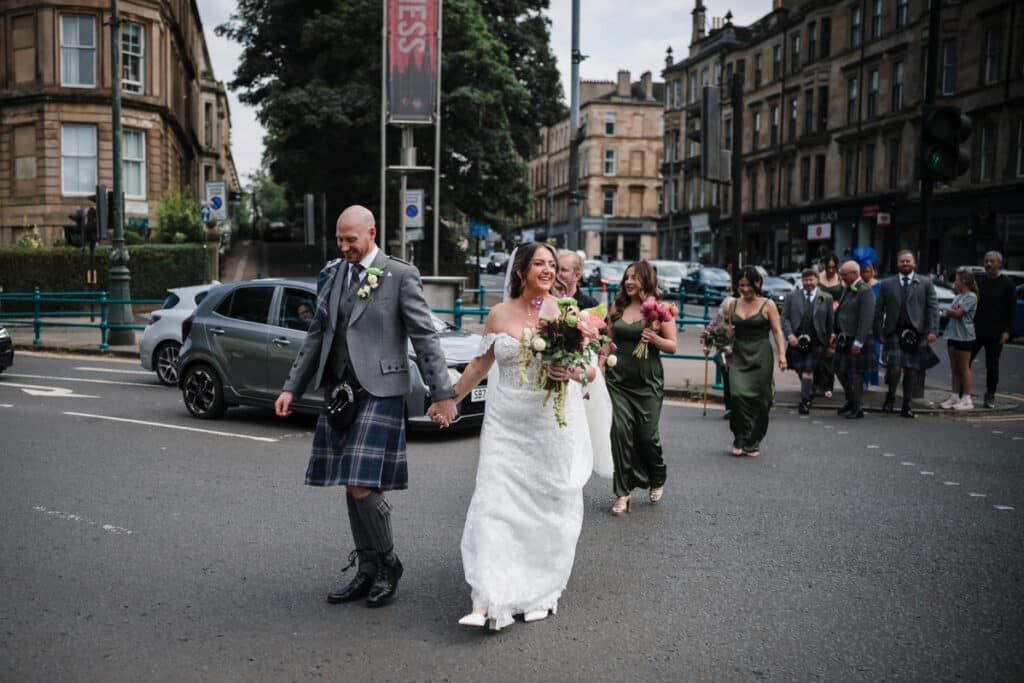 Bride, groom and bridal party cross the street outside Oran Mor in Glasgow's West End