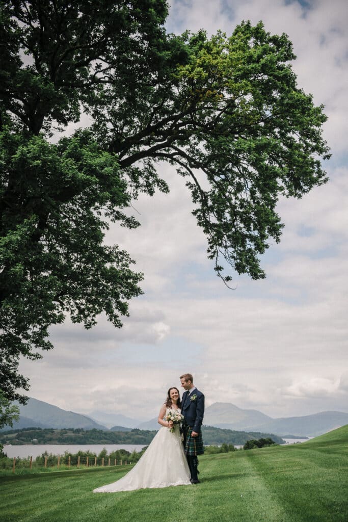 Boturich Castle Wedding photo with bride and groom by a tree, overlooking Loch Lomond