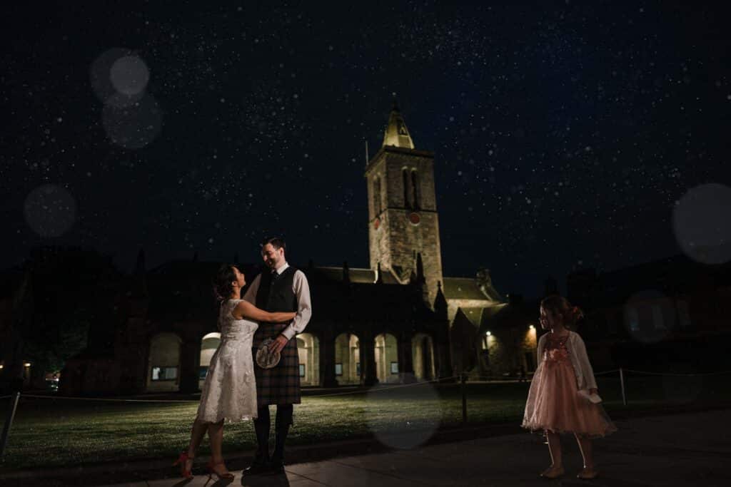 Bride and Groom stand outside St Salvator's in St Andrews at Night
